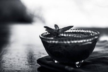 Ilımlı sabja tohumları veya falooda tohumları veya tatlı fesleğen tohumları ahşap yüzeyüzerinde kahverengi renkli peçete üzerinde cam bir kase içinde bazı nane yaprakları ile kapatın. Birçok aromalı içecekte kullanılır.