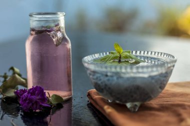 Popüler Hint ve Asya şerbedi yani Gulab ka şerbat veya gül sütü ahşap yüzeyüzerinde hangi batırılmış kefalet tohumları ve gül konsantrasyonu veya özü malzemeler yakın.