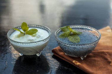 Ağırlığı azaltmak için en iyi ve en etkili yöntem yani ıslatılmış tatlı fesleğen tohumları iyi lor veya yoğurt karışık. Ahşap yüzeyde tüm ham maddeler.