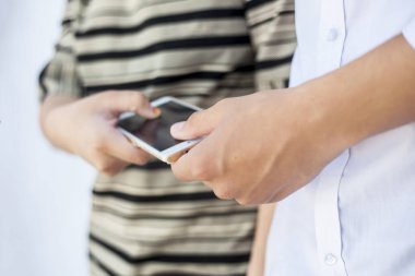 Cep telefonlarını paylaşan iki çok etnik arkadaşın ellerini kapatın.