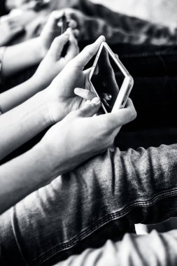 Bir duvarda oturan ve akıllı telefonlar kullanarak ve arkadaşlarınızla vakit geçirmek genç sadece elleri ve bacakları kapatın.