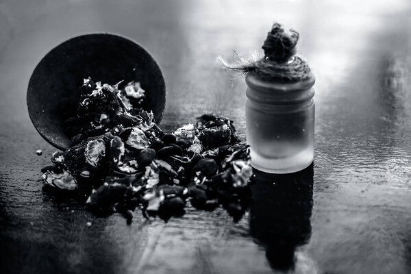Tamarind or imli or amli in a clay bowl along with its roasted seeds and extract essential oil in a glass bottle on wooden surface.