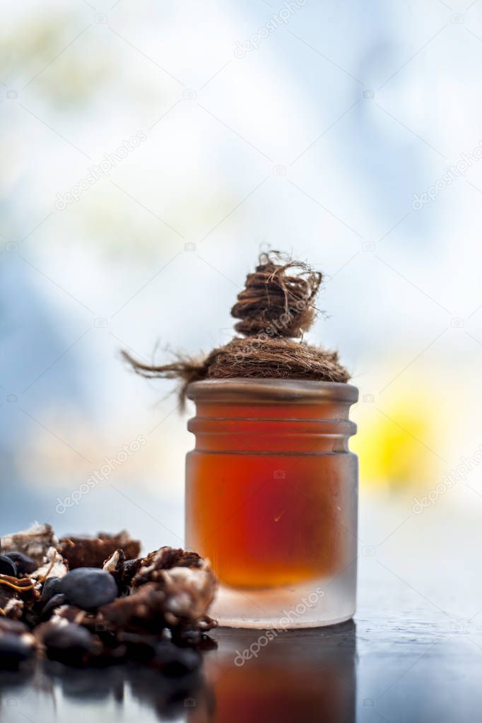 Tamarind or imli or amli in a clay bowl along with its roasted seeds and extract essential oil in a glass bottle on wooden surface.