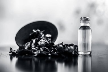 Kavrulmuş tohumları ile birlikte kil bir kapta demirhindi veya imli veya amli ve siyah renkli ahşap yüzey üzerinde bir cam şişe esansiyel yağ veya konsantrasyon veya özü ayıklayın.