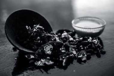 Kavrulmuş tohumları ve çıkarılan macunu veya tentürü ile birlikte kil bir kapta demirhindi veya imli veya amli tahta yüzeyinde kavrulmuş demirhindi tohumu tozu ile birlikte cam bir kapta.