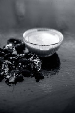 Kavrulmuş tohumları ve çıkarılan macunu veya tentürü ile birlikte kil bir kapta demirhindi veya imli veya amli tahta yüzeyinde kavrulmuş demirhindi tohumu tozu ile birlikte cam bir kapta.