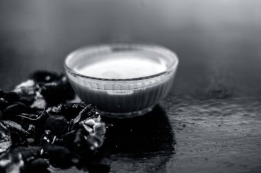 Kavrulmuş tohumları ve çıkarılan macunu veya tentürü ile birlikte kil bir kapta demirhindi veya imli veya amli tahta yüzeyinde kavrulmuş demirhindi tohumu tozu ile birlikte cam bir kapta.