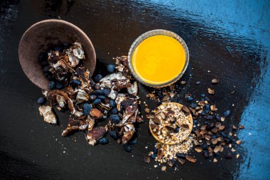 Kavrulmuş tohumları ve çıkarılan macunu veya tentürü ile birlikte kil bir kapta demirhindi veya imli veya amli tahta yüzeyinde kavrulmuş demirhindi tohumu tozu ile birlikte cam bir kapta.