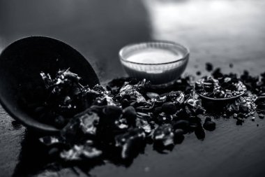 Kavrulmuş tohumları ve çıkarılan macunu veya tentürü ile birlikte kil bir kapta demirhindi veya imli veya amli tahta yüzeyinde kavrulmuş demirhindi tohumu tozu ile birlikte cam bir kapta.