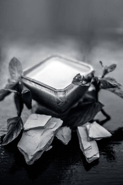 Fuller toprak veya mulpani mitti veya multani mitti veya ağartma kil iyi mavi renkli cam kase içinde bazı nane yaprakları ile birlikte ahşap yüzeyde dekorasyon için bazı nane yaprakları ile karışık.