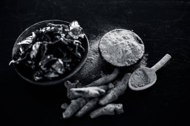 Akne ve sivilce tedavisinde kullanılan kil kase zerdeçal veya haldi ile ahşap yüzeyüzerinde kavrulmuş tohumları ile birlikte bir kil kase içinde demirhindi veya imli veya amli.