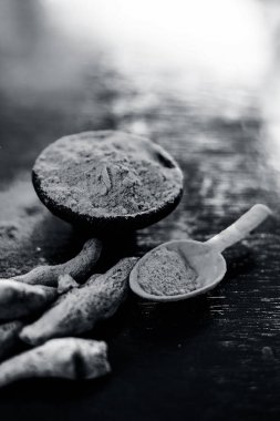 Çiğ organik ünlü ve temel baharat yani Zerdeçal veya haldi veya Curcuma veya Curcuma, safran des Indes bir kil kase kahverengi renkli ahşap yüzey üzerinde toz ile birlikte.