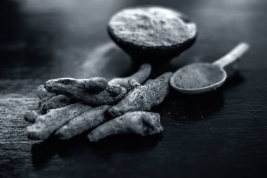 Çiğ organik ünlü ve temel baharat yani Zerdeçal veya haldi veya Curcuma veya Curcuma, safran des Indes bir kil kase kahverengi renkli ahşap yüzey üzerinde toz ile birlikte.