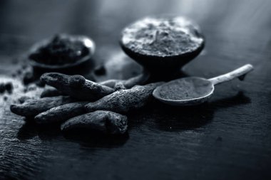 Parlak yüzeyüzerinde başka bir kase bazı ham zerdeçal ve siyah tuz ile birlikte zerdeçal tozu dolu kil kase yakın.