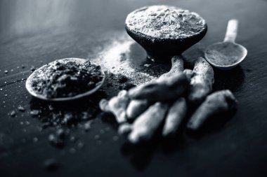 Parlak yüzeyüzerinde başka bir kase bazı ham zerdeçal ve siyah tuz ile birlikte zerdeçal tozu dolu kil kase yakın.