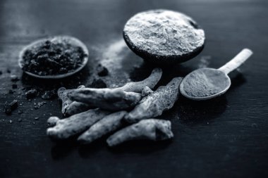 Parlak yüzeyüzerinde başka bir kase bazı ham zerdeçal ve siyah tuz ile birlikte zerdeçal tozu dolu kil kase yakın.