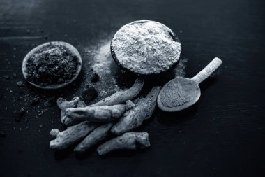 Parlak yüzeyüzerinde başka bir kase bazı ham zerdeçal ve siyah tuz ile birlikte zerdeçal tozu dolu kil kase yakın.