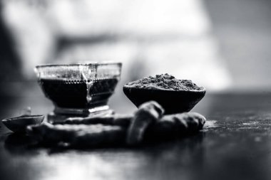 Akne ve sivilce tedavisinde kullanılan kil kase zerdeçal veya haldi ile ahşap yüzeyüzerinde kavrulmuş tohumları ile birlikte bir kil kase içinde demirhindi veya imli veya amli.