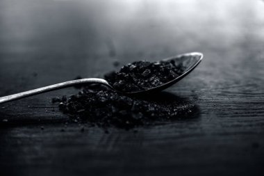 Ahşap yüzeyüzerinde altın bir kaşıkta ham organik kaya tuzu veya sendha namak veya kala namak.