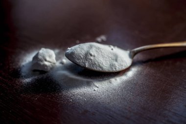 Ahşap yüzeyüzerinde altın renkli kaşıkta ham kabartma tozu veya kabartma tozu.