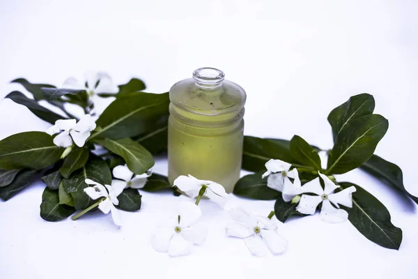 White colored flowers along with leaves and essential herbal detoxifying oil in a glass bottle isolated on white.