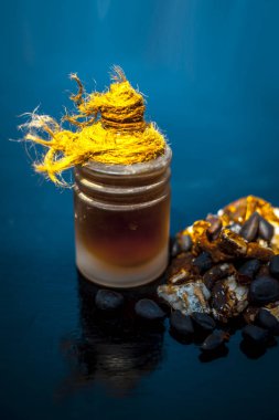 Ham organik amli veya demirhindi veya imli şeffaf bir cam şişe onun çıkarılan bitkisel uçucu yağ ile ahşap yüzeyüzerinde bir kil kase içinde.