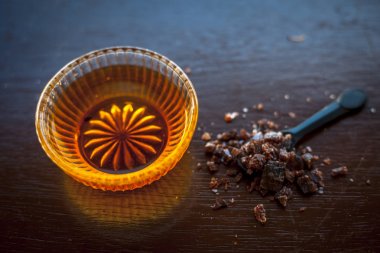 Siyah renkli kaşık toz kaya çıta ile birlikte ahşap yüzeyüzerinde bir cam kase içinde ham bal kapatın. İyi bir uyku elde yardımcı olur.