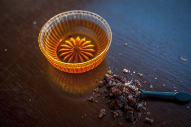 Siyah renkli kaşık toz kaya çıta ile birlikte ahşap yüzeyüzerinde bir cam kase içinde ham bal kapatın. İyi bir uyku elde yardımcı olur.