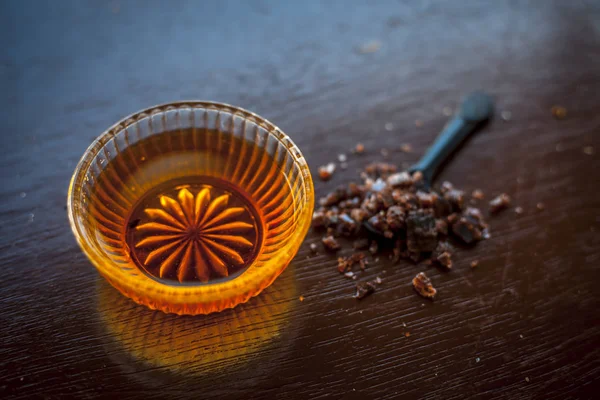 Siyah renkli kaşık toz kaya çıta ile birlikte ahşap yüzeyüzerinde bir cam kase içinde ham bal kapatın. İyi bir uyku elde yardımcı olur.