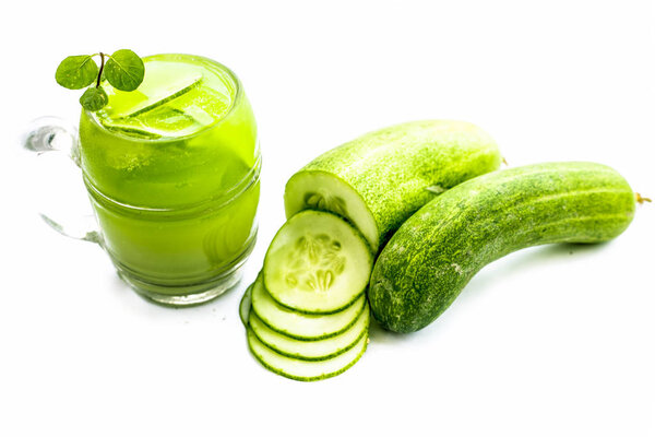 Raw extracted Cucumber juice in a transparent glass isolated on white along with raw fresh cucumber and slices,also.