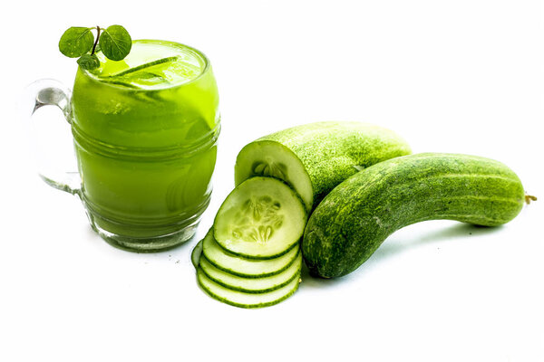 glass of cucumber smoothie with cucumbers isolated on white