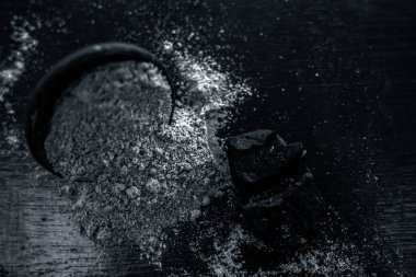 Ham organik menting veya şeytan gübresi veya Asafoetida siyah renkli kil kase ve bazı nane yaprakları veya mentha yaprakları onun tozu ile birlikte ahşap yüzeyüzerinde.