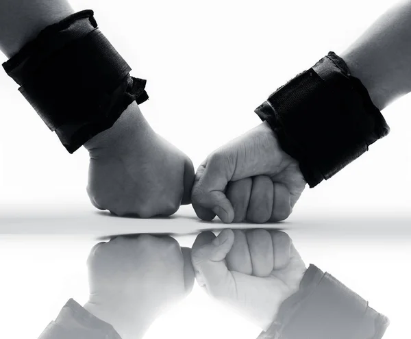 Two hands wearing black colored wrist weights or wrist bands isolated on white along with its reflection also.