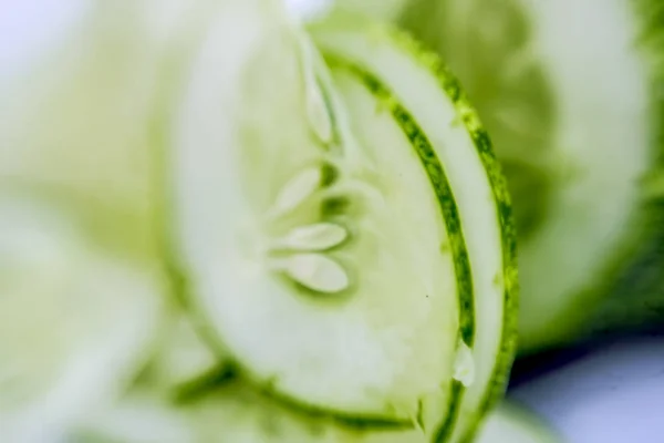 Macro shot of raw cut slices of cucumber isolated on white.