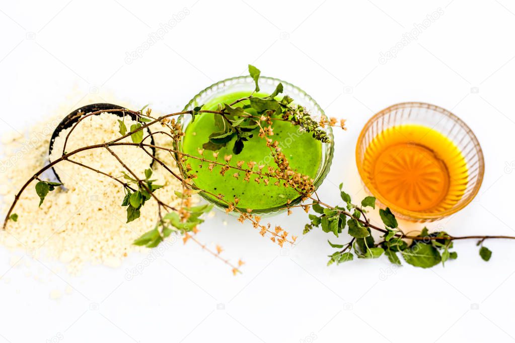 Basil face mask isolated on white i.e. Basil leaves juice well mixed with honey and gram flour in a bowl and entire raw ingredients present on the surface.Used for instant acne and pimple free glow.