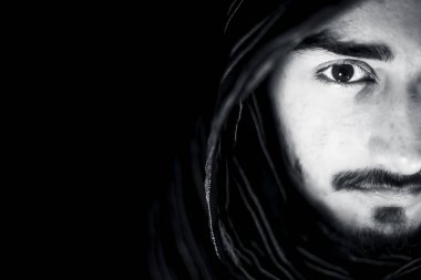 Siyah beyaz renkli bir adamın yüzünde ki öfkeyi ifade eden ve yüzünde siyah renkli bez giyen siyah renkli bir portre fotoğrafı.