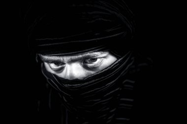 Erkek genç çarpıcı portre gözleri dışında yüz kapsayan bir bez ile birlikte delici ifade gözleri ile siyah izole. Cesaret ve sarışınlık ifade.