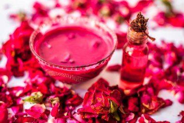 Bazı uçucu yağ veya yüzeye yayılmış bazı gül yaprakları ile birlikte bir cam şişede gül konsantrasyonu ile bir cam kase Gül Reçeli.