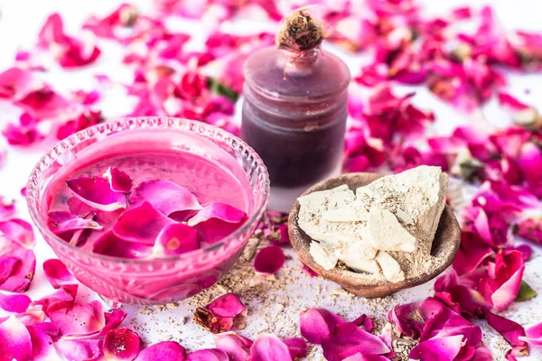 Rose water face pack isolated with rose petals well mixed with mulpani mitti or fuller\'s earth in a glass bowl and entire ingredients present on the surface,Used  For Exfoliation.
