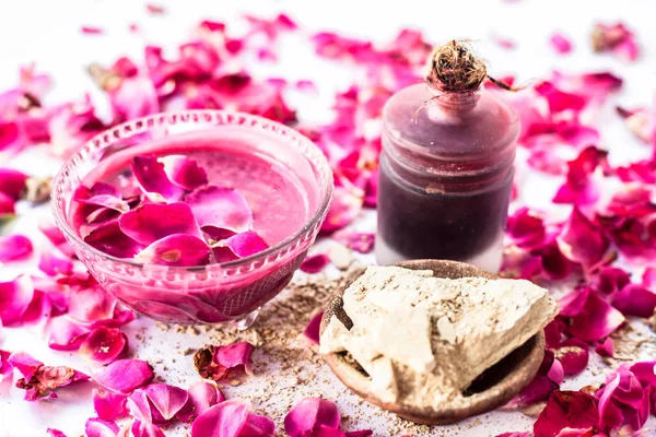 Rose water face pack isolated with rose petals well mixed with mulpani mitti or fuller's earth in a glass bowl and entire ingredients present on the surface,Used  For Exfoliation.