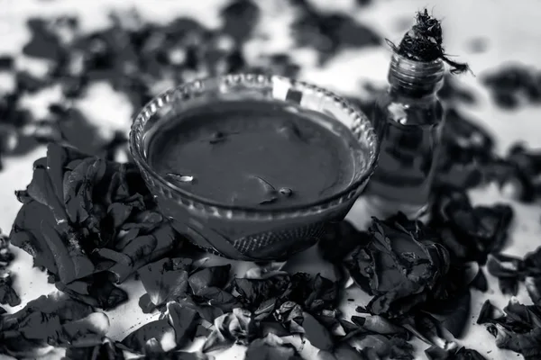 Bazı uçucu yağ veya yüzeye yayılmış bazı gül yaprakları ile birlikte bir cam şişede gül konsantrasyonu ile bir cam kase Gül Reçeli.