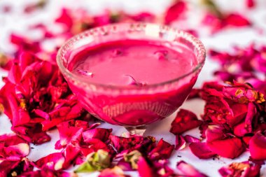 Bazı uçucu yağ veya yüzeye yayılmış bazı gül yaprakları ile birlikte bir cam şişede gül konsantrasyonu ile bir cam kase Gül Reçeli.