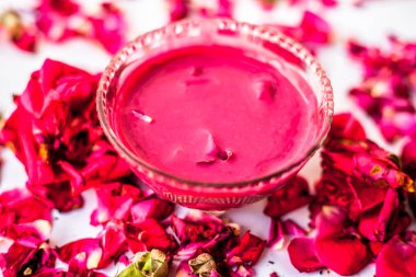 Bazı uçucu yağ veya yüzeye yayılmış bazı gül yaprakları ile birlikte bir cam şişede gül konsantrasyonu ile bir cam kase Gül Reçeli.