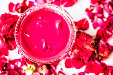 Bazı uçucu yağ veya yüzeye yayılmış bazı gül yaprakları ile birlikte bir cam şişede gül konsantrasyonu ile bir cam kase Gül Reçeli.