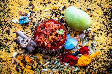 Siyah renkli parlak yüzey üzerinde tüm malzemeyi ile cam bir tabak ta Aam ka achar veya keri ka achar.