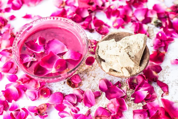 Rose flower face pack isolated with rose petals well mixed with mulpani mitti or fuller\'s earth in a glass bowl and entire ingredients present on the surface,Used to  soak excess oil from face.