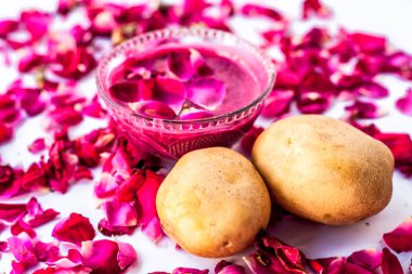 En iyi yüz maskesi veya yüz paketi lekeleri ve koyu yamalar beyaz yani gül yaprakları iyi bir kase ve çiğ patates ve gül yaprakları yüzeyde mevcut patates suyu ile karışık izole azaltmak için.