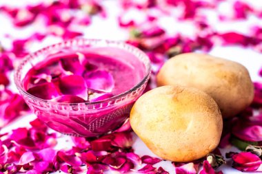 En iyi yüz maskesi veya yüz paketi lekeleri ve koyu yamalar beyaz yani gül yaprakları iyi bir kase ve çiğ patates ve gül yaprakları yüzeyde mevcut patates suyu ile karışık izole azaltmak için.