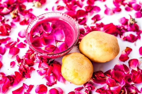 En iyi yüz maskesi veya yüz paketi lekeleri ve koyu yamalar beyaz yani gül yaprakları iyi bir kase ve çiğ patates ve gül yaprakları yüzeyde mevcut patates suyu ile karışık izole azaltmak için.