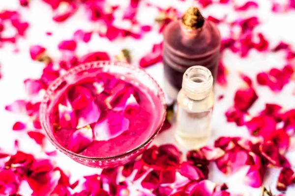 Rose face pack for dry skin isolated on white i.e. Rose petals well mixed with rose oil and glycerin in a glass bowl and entire raw ingredients present.